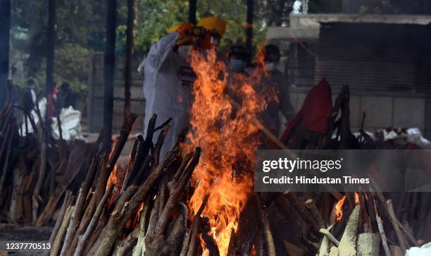 Volunteers and relatives perform the last rites of a Covid-19 victim, at Seemapuri cremation ground, on January 16, 2022 in New Delhi, India.