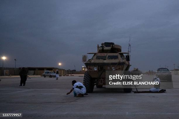 In this photograph taken on January 16 Taliban fighters prepare to offer prayers next to a parked armored vehicle after taking part in a military...