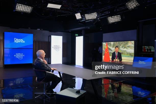 Founder and Executive Chairman of the World Economic Forum Klaus Schwab listen Chinese President Xi Jinping seen on the TV screen speaking remotely...