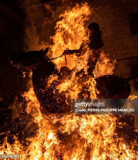 Horseman rides through a bonfire in the village of San Bartolome de Pinares in the province of Avila in central Spain, during the traditional...