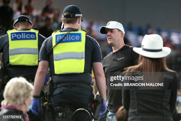 Spectator is escorted out of the Rod Laver Arena by police on day one of the Australian Open tennis tournament in Melbourne on January 17, 2022. - --...