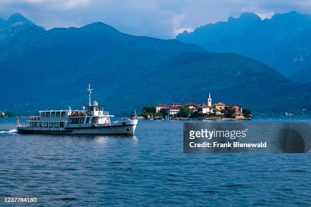 View to the island Isola Superiore, the tower of the church of San Vittore standing out, over Lake Maggiore, surrounding mountains in the distance, a...