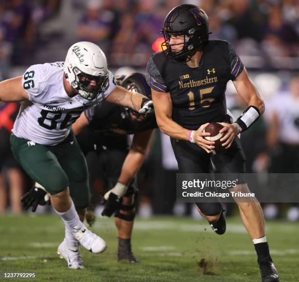 Northwestern quarterback Hunter Johnson tries to elude the Michigan State defense in the second half of a game at Ryan Field in Evanston, Illinois,...