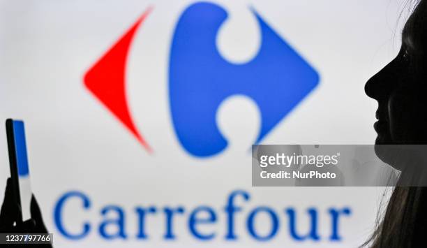 An image of a woman holding a cell phone in front of the Carrefour logo displayed on a computer screen. On Tuesday, January 12 in Edmonton, Alberta,...