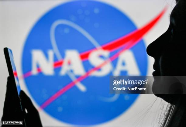 An image of a woman holding a cell phone in front of the NASA logo displayed on a computer screen. On Tuesday, January 12 in Edmonton, Alberta,...