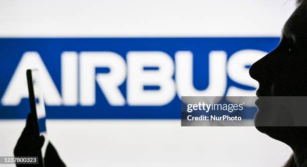 An image of a woman holding a cell phone in front of the Airbus logo displayed on a computer screen. On Tuesday, January 12 in Edmonton, Alberta,...