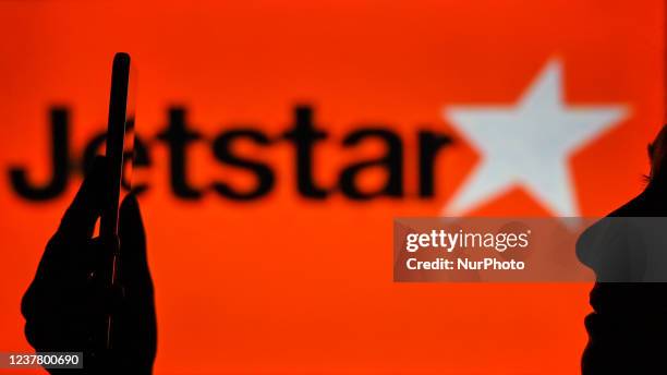 An image of a woman holding a cell phone in front of the Jetstar Airways logo displayed on a computer screen. On Tuesday, January 12 in Edmonton,...