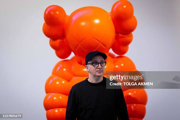 American artist Kaws, real name Brian Donnelly, poses with an artwork titled KAWS WHAT PARTY during a press preview for the exhibition 'KAWS: NEW...