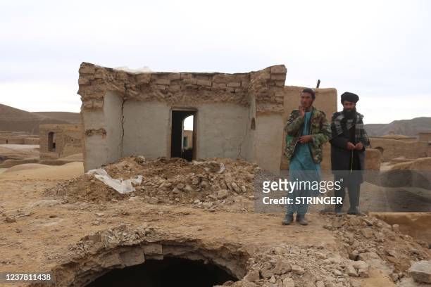 Local residents stand near a damaged house at Qadis district in Afghanistan's western Badghis Province, on January 18 after an earthquake hit the...