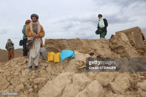 Local residents stand near a damaged house at Qadis district in Afghanistan's western Badghis Province, on January 18 after an earthquake hit the...