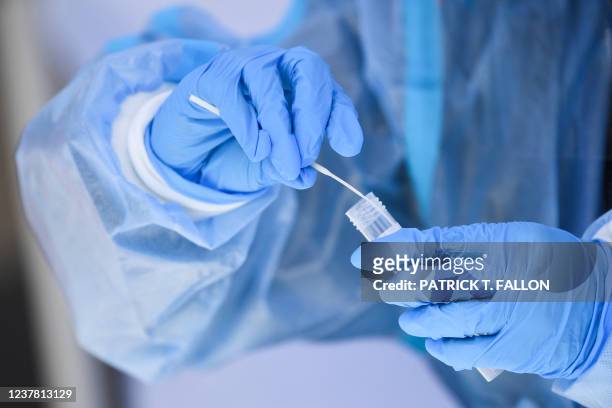 Healthcare worker places a test swab into solution for a PCR Covid-19 test at a Reliant Health Services testing site in Hawthorne, California on...