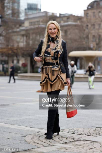 Influencer Gunhild Busch wearing a light brown mini dress with ruffle detail by Twinset, a checkered scarf by Burberry, a black jacket by Babor, a...