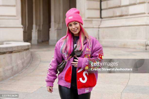 Influencer Chany Dakota wearing a black top by Brandy Melville, a multicolored varsity jacket by Supreme x Skittles x Mitchell & Ness, a dark brown...