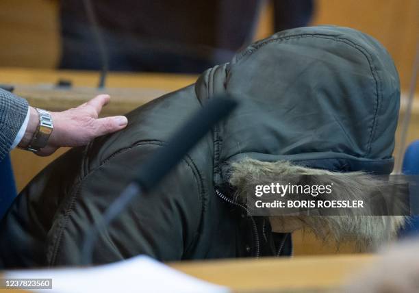 Defendant Alaa M, accused of crimes against humanity including torture and murder in his war-torn homeland Syria, hides under the hood of his jacket...