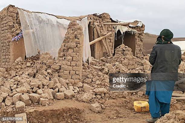 In this photo taken on January 18 a resident stands near a damaged house at Qadis district in the southern part of Badghis province, after an...