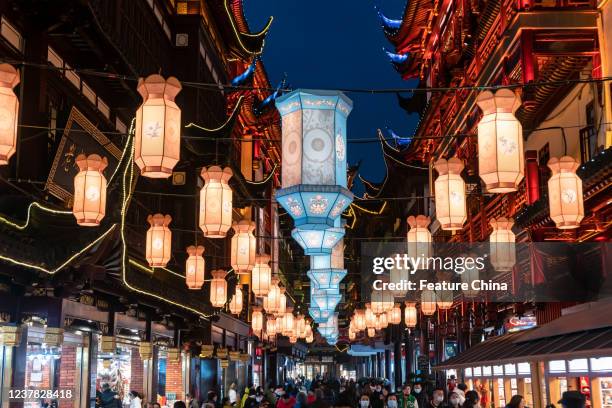 People walk under a lantern arcade in Yu Garden during the Spring Festival lantern show in Shanghai, China Wednesday, Jan. 19, 2022.