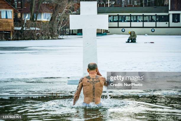 Man with christian tatoos crosses himself in a bath in iced waters of a lake during the celebrations of the Epiphany in Kyiv,Ukraine.