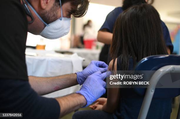 Registered nurse Randall Brown puts a bandaid on a girl's arm after administering a pediatric dose of the Covd-19 vaccine at a L.A. Care Health Plan...