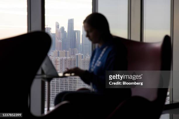 An employee works at a laptop computer overlooking skyscraper office buildings in the Moscow International Business Center , also known as Moscow...