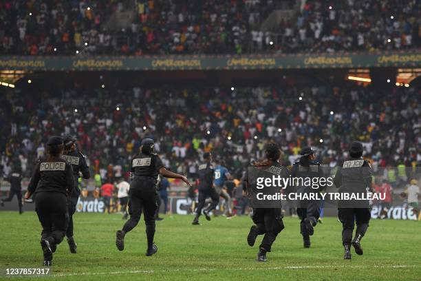 Cameroonian police officers run onto the pitch as people invade the pitch after the Group E Africa Cup of Nations 2021 football match between Ivory...