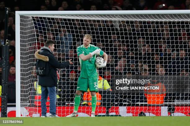 Pitch invader offers to shake hands with Arsenal's English goalkeeper Aaron Ramsdale during the English League Cup semi-final second leg football...