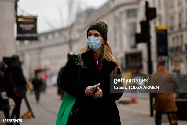 Woman wearing a face mask walks in London on January 21, 2022. - The UK government announced this week that restrictions reimposed in England last...