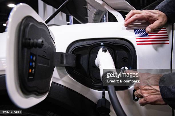 An exhibitor demonstrates plugging in a charging port for a Ford Motor Co. Mustang during the Washington Auto Show in Washington, D.C., U.S., on...