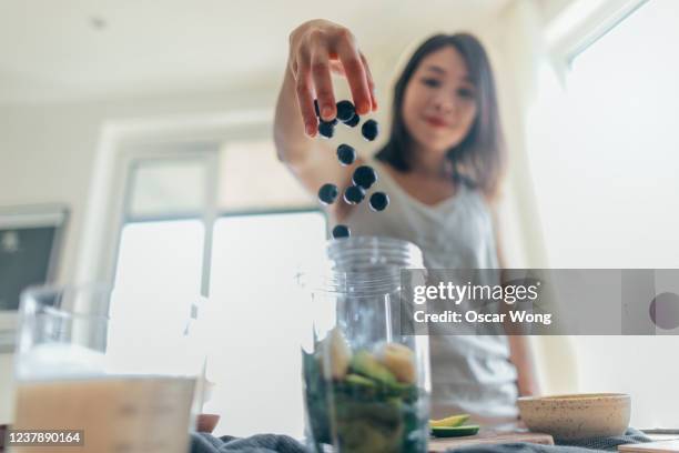 young woman making healthy smoothie for breakfast - saftpresse stock-fotos und bilder