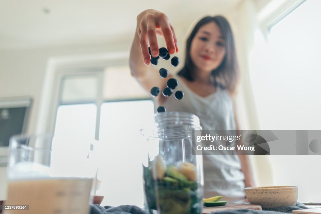 Young Woman Making Healthy Smoothie For Breakfast