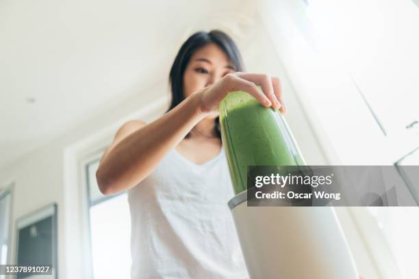 young woman making healthy green smoothie for breakfast - kitchen low angle stock pictures, royalty-free photos & images