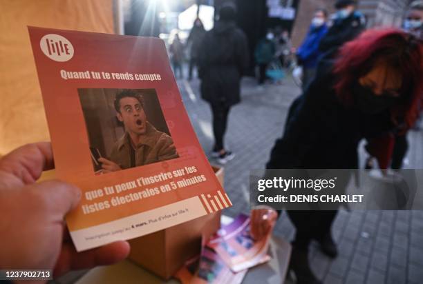 An employee of the town hall of Lille holds a leaflet to convince the citizens to register on the electoral rolls in Lille, on January 25, 2022. - A...