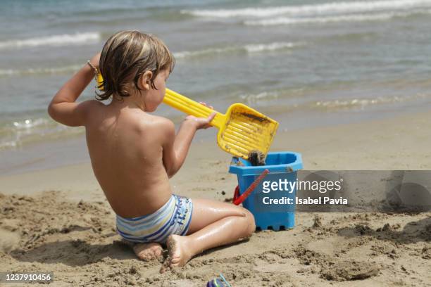 little boy building sandcastles at the beach - sand castle bildbanksfoton och bilder
