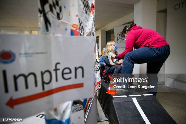 Girl is being vaccinated by a doctor with the BioNTech/Pfizer vaccine dosed for children at a test and vaccination centre set up at a car dealership...