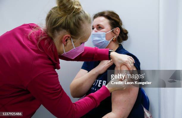 Woman is being vaccinated by a doctor with the BioNTech/Pfizer vaccine at a test and vaccination centre set up at a car dealership as the spread of...