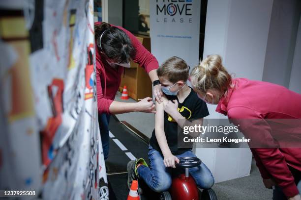 Boy is being vaccinated by a doctor with the BioNTech/Pfizer vaccine dosed for children at a test and vaccination centre set up at a car dealership...