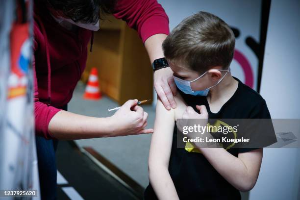 Boy is being vaccinated by a doctor with the BioNTech/Pfizer vaccine dosed for children at a test and vaccination centre set up at a car dealership...