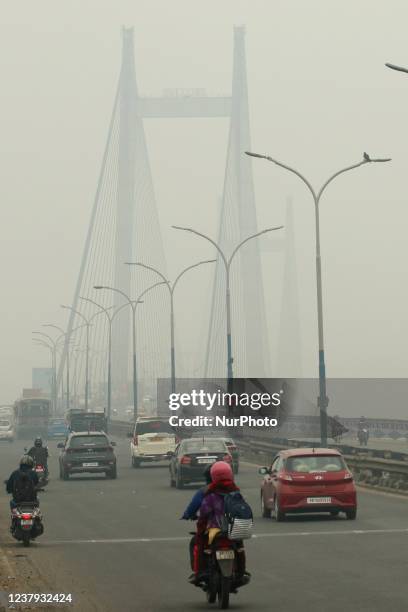 Indian commuters cross the Vidyasagar Bridge a Foggy morning over the Ganga River amid Coronavirus emergency on January 23, 2022 in Kolkata, West...