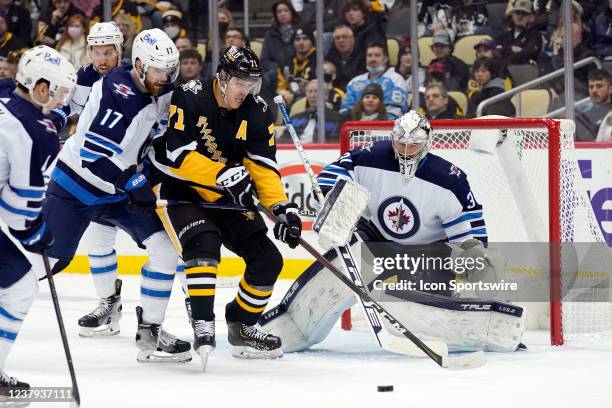 Pittsburgh Penguins Center Evgeni Malkin plays the puck in front of Winnipeg Jets Goalie Connor Hellebuyck as Winnipeg Jets Center Adam Lowry defends...