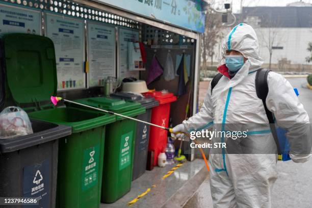 This photo taken on January 23, 2022 shows a staff member spraying disinfectant at a residental area as the city starts to reopen after a Covid-19...