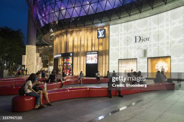 Visitors sit outside Ion Orchard mall on Orchard Road in Singapore on Saturday, Jan. 22, 2022. Firmer local demand from reopening and external supply...