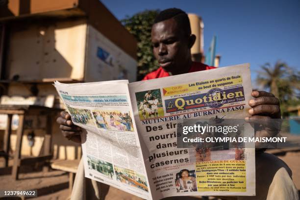 Man a newspaper with the headline on the mutiny in Ouagadougou on January 24, 2022. - The President of Burkina Faso, Roch Marc Christian Kaboré, was...