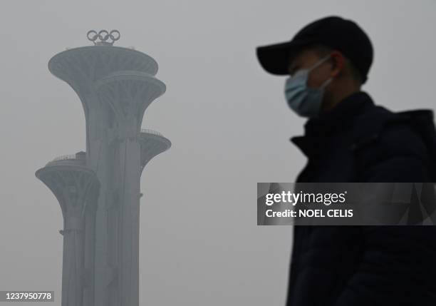 Man walks in the Olympic Park during a smoggy day in Beijing on January 24, 2022.