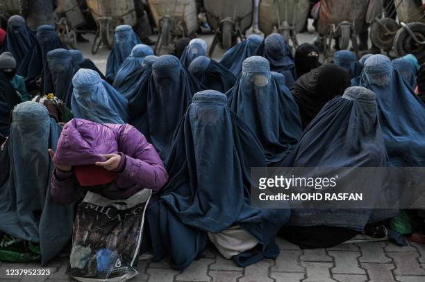 Women wearing a burqa wait for free bread in front of a bakery in Kabul on January 24, 2022.
