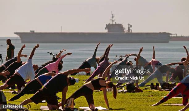 January 24: A group does yoga as the decommissioned United States Navy supercarrier USS Kitty Hawk passes by Long Beach on its final voyage from the...