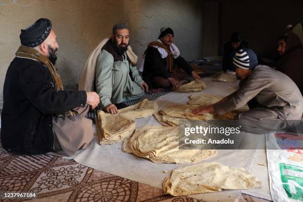 Men are seen with bread made by Afghan women at a bakehouse in Kandahar, Afghanistan on January 24, 2022. A private firm offered employment...