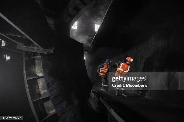 Workers clean a wagon after unloading coking coal at the Moscow coke and gas plant, operated by Mechel PJSC, in Vidnoye, near Moscow, Russia, on...