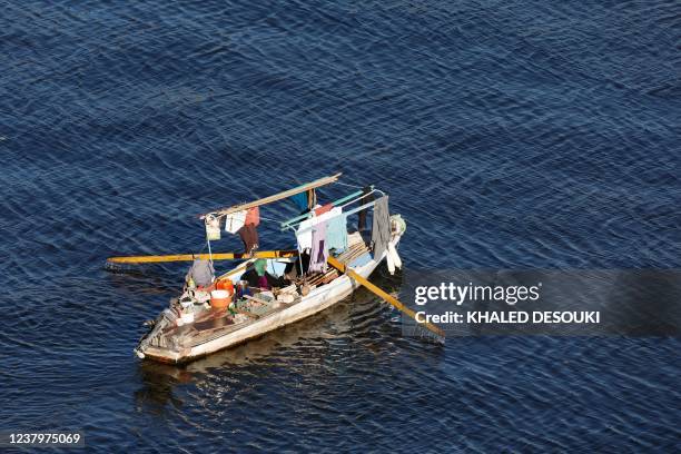 Members of a family of fishermen sit in a fishing boat in the Nile river in Egypt's capital Cairo on January 25, 2022.