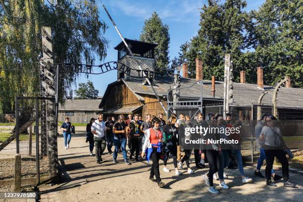 Visitors walk through the entrance gate with 'Arbeit Macht Frei' inscription in the former Nazi German Auschwitz I concentration camp at Auschwitz...