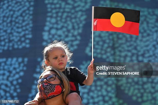 Young girl holds up an Australian Aboriginal flag during an "Invasion Day" demonstration on Australia Day in Sydney on January 26, 2022.
