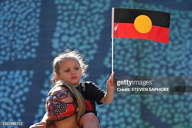 Young girl holds up an Australian Aboriginal flag during an "Invasion Day" demonstration on Australia Day in Sydney on January 26, 2022.